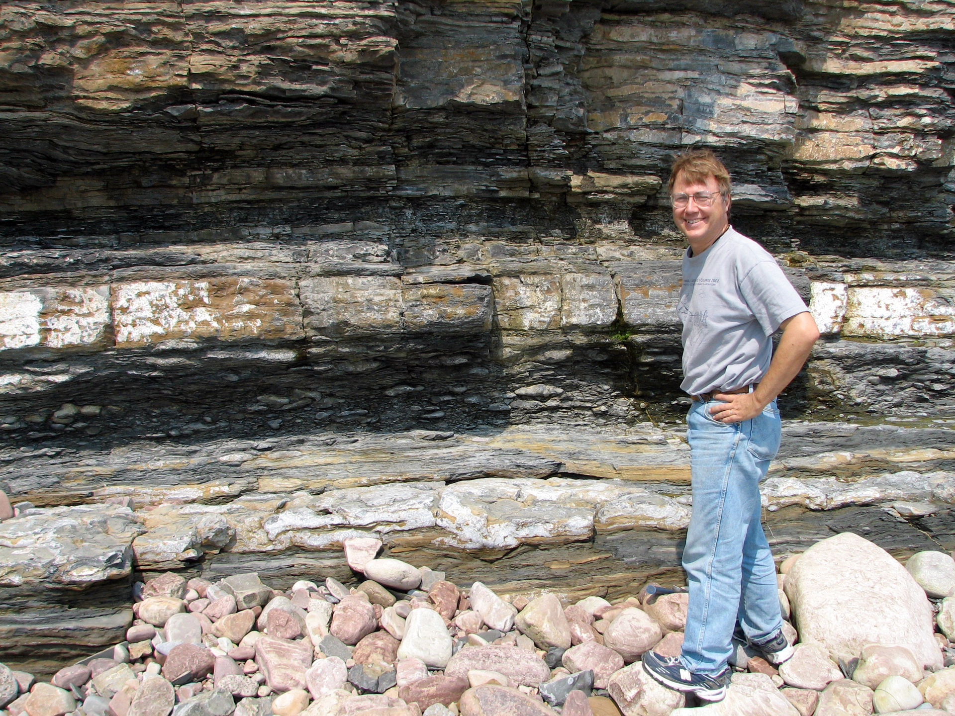Andrew Knoll standing in front of a vibrant formation of geological strata
