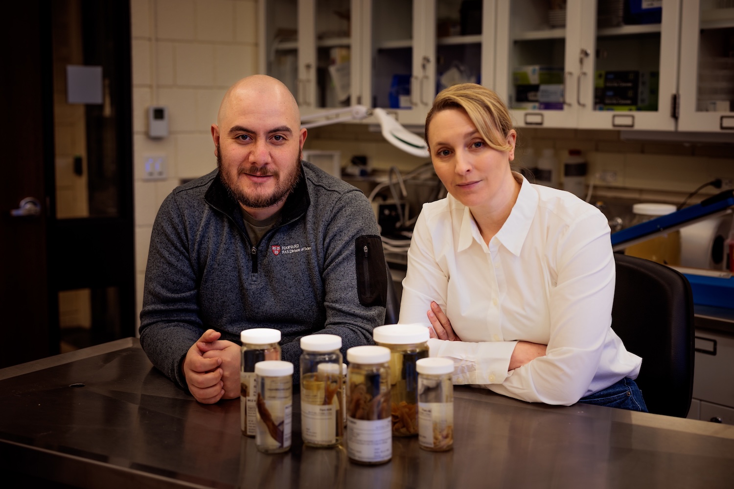 A faculty and a postdoctoral fellow stand at a counter with samples of fish.
