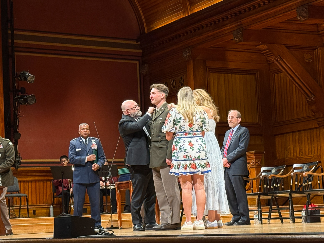 Jack Martin, in uniform, having his officer bars pinned on his uniform by his family on stage