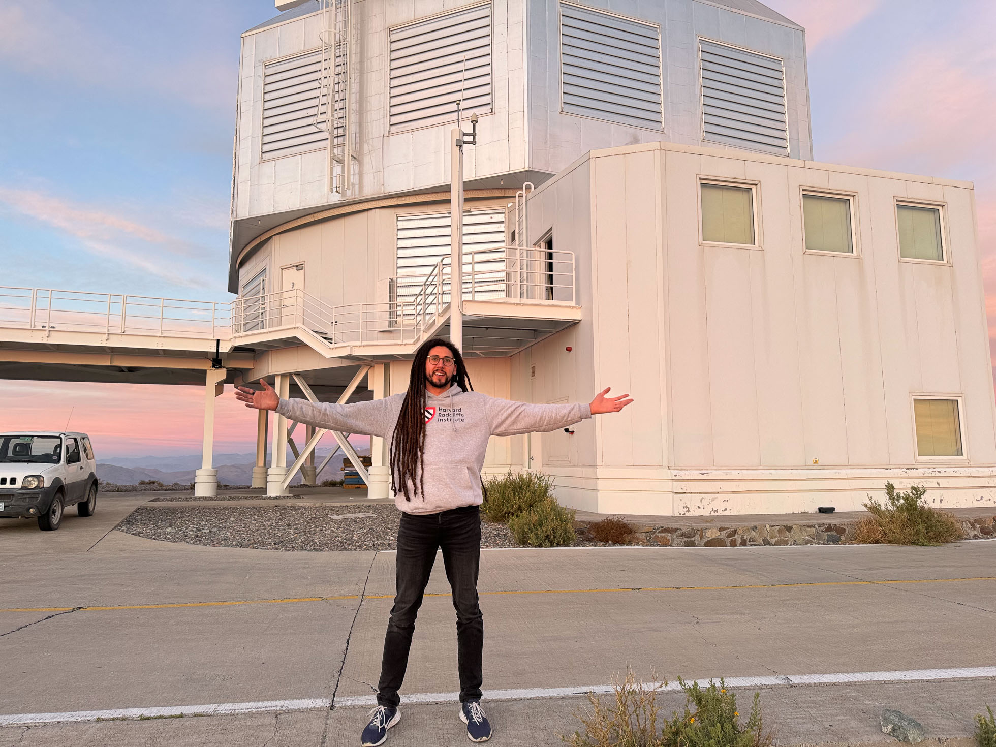 Collin Cherubim standing outside Las Campanas Observatory in Chile, arms outstretched
