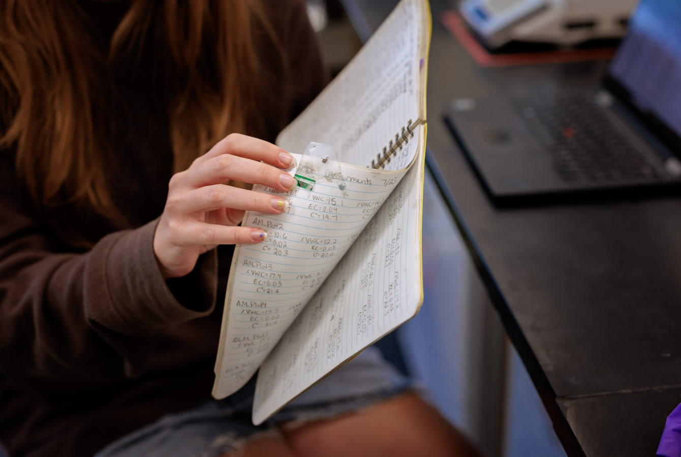 Close-up of Harvard Forest Summer Program Kyla Ritchie flipping through her notebook