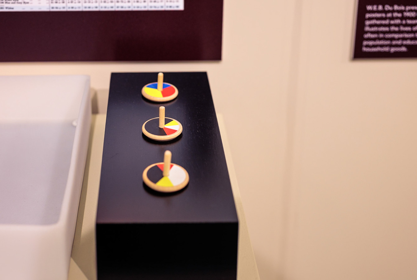 Three toy spinning tops with mixed colors on top in a display case