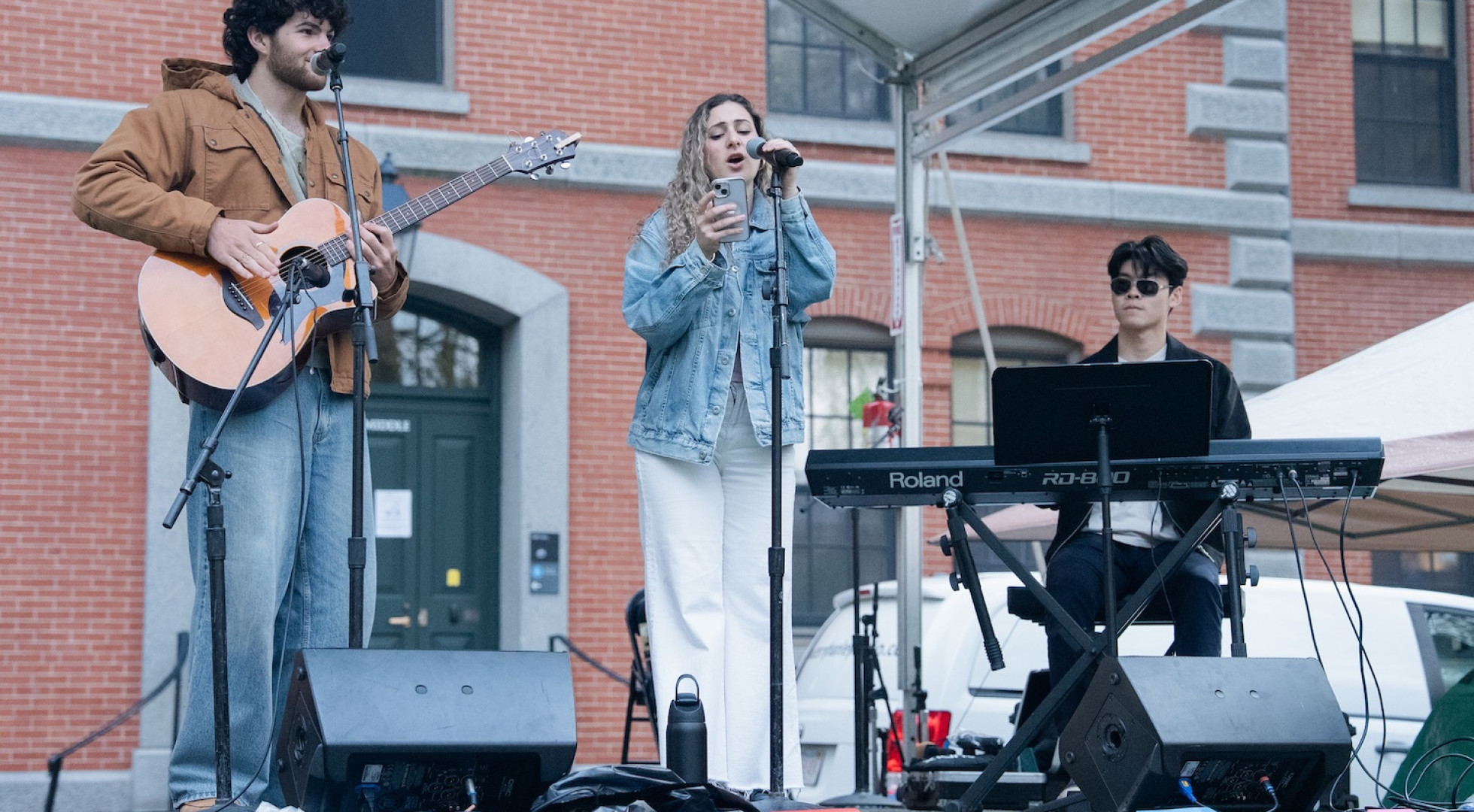 Harvard College student Dessa Kavrakis, at center, performed on a stage in Harvard Yard with classmates Jude Partovi and Marcus Lee.