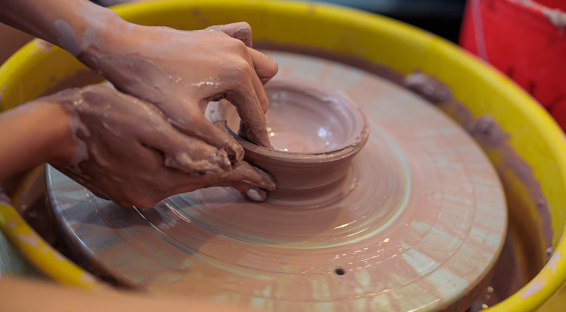 Close-up shot of two hands shaping pottery on a wheel