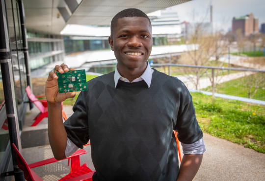 Harvard electrical engineering student Ike Ogbu holidng a circuit board