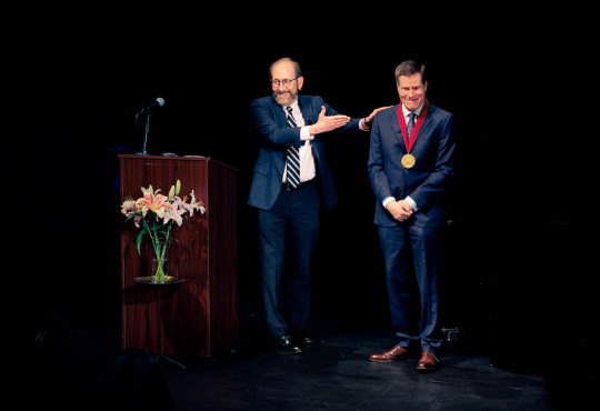 Harvard President Alan Garber, at left, presented theater director Bill Rauch with the 2026 Harvard Arts Medal in a ceremony Sunday at Farkas Hall.