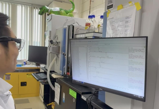 Profile of Alan wong in lab gear looking at a computer