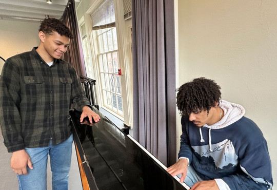 Quadree "Dree" Palimore ’26 playing a piano while Yerim Colin ’27 stands alongside