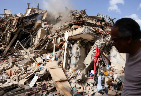 View of a large pile of rubble and a man searching through it