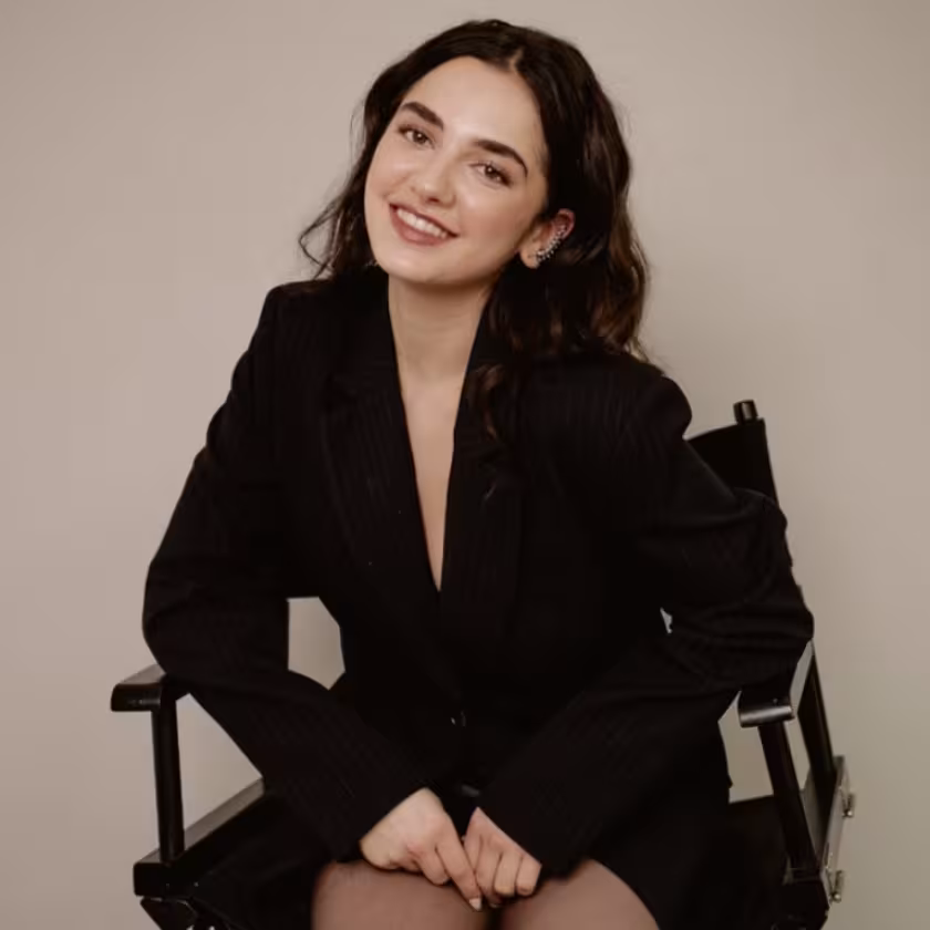 Mattea Conforti ’28 smiles in a director's chair, wearing a black pinstripe blazer.