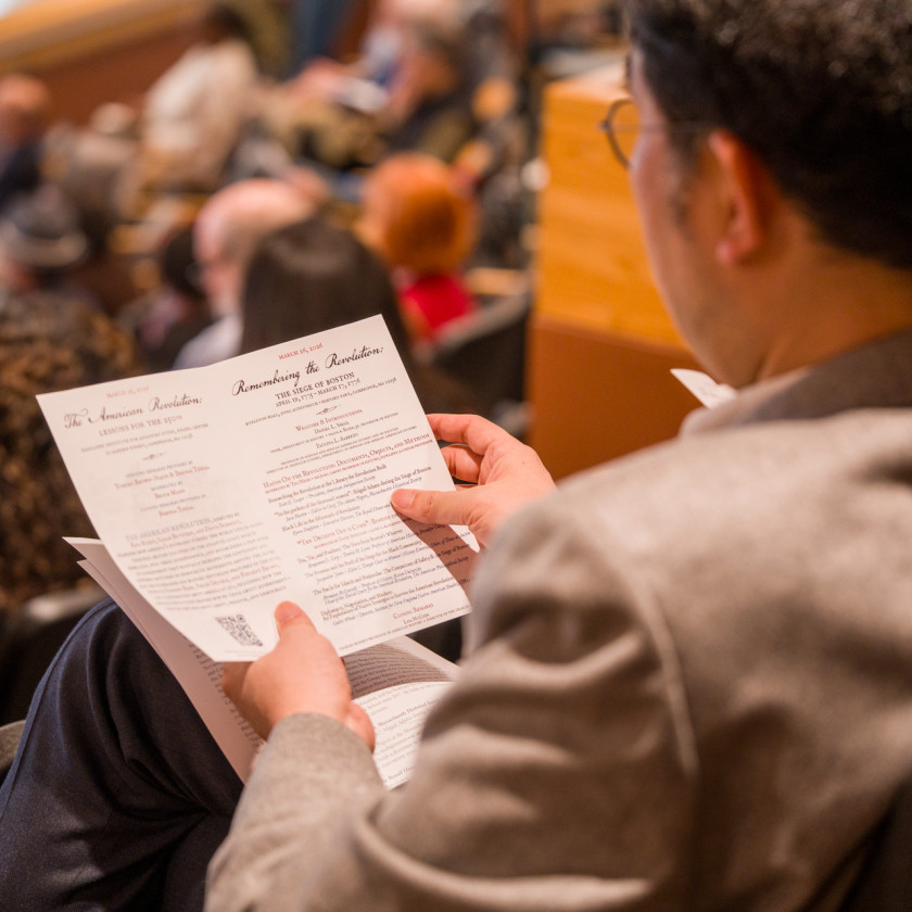 An attendee in Fong Auditorium peruses the ”Harvard in 1776“ program