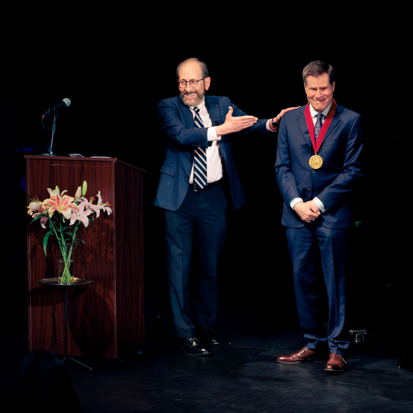 Harvard President Alan Garber, at left, presented theater director Bill Rauch with the 2026 Harvard Arts Medal in a ceremony Sunday at Farkas Hall.
