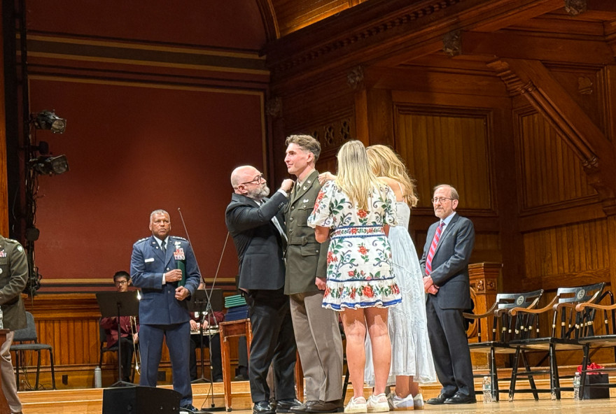Jack Martin, in uniform, having his officer bars pinned on his uniform by his family on stage