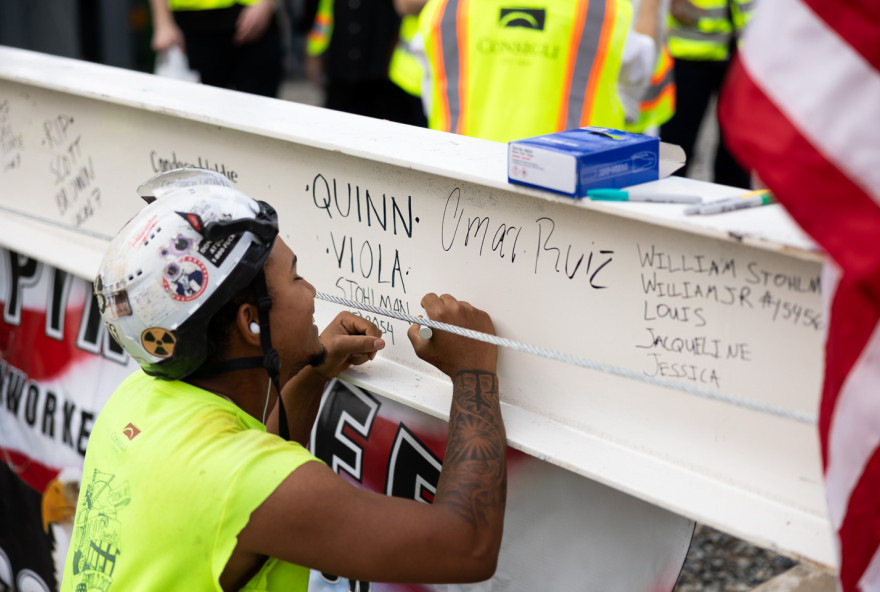 A construction worker signs a message on an iron beam