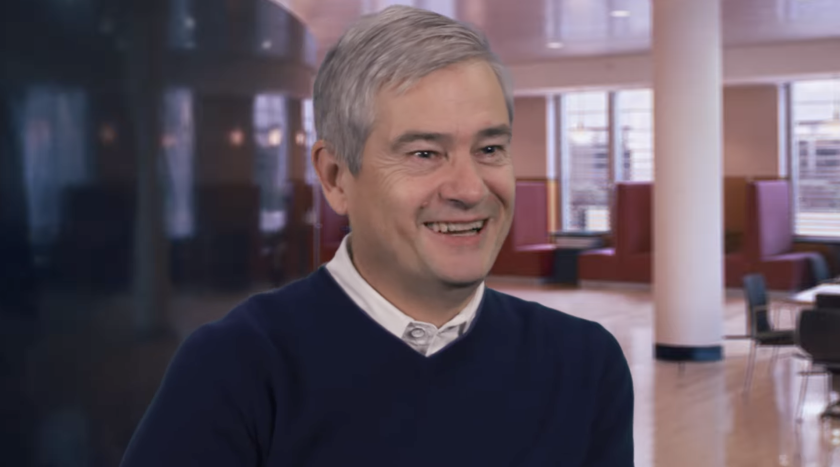 Professor Steve Ansolabehere smiles wearing a collared shirt and sweater