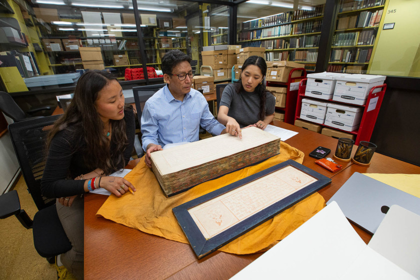 Tibetan language instructor Karma Gongde studies the Tibetan Buddhist canon at Harvard–Yenching Library with students Tenzin Yiga ’28 and Tsering Yangchen ’26.
