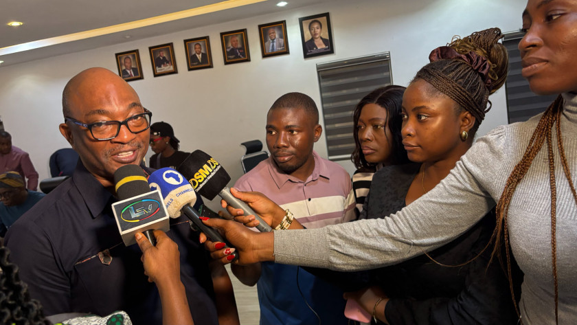 Emmanuel Akyeampong at left speaking into microphones held by reporters