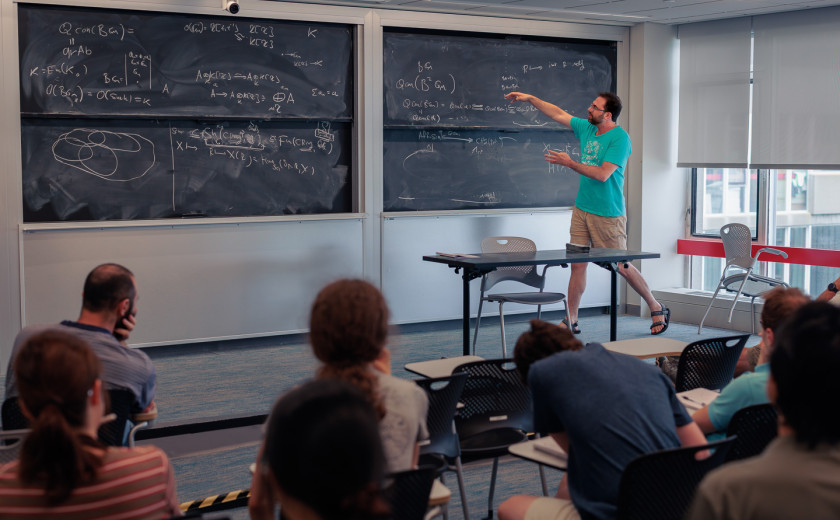 Tomer Schlank, professor of mathematics, gesturing to a chalkboard